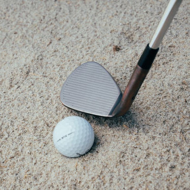 TaylorMade Hi-Toe 3 in a sandy bunker at the address of a TaylorMade TP5 Golf Ball