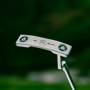 TaylorMade TP Reserve B11 L-Neck Golf Putter being held up so the sole of the club is visible on a green natural background