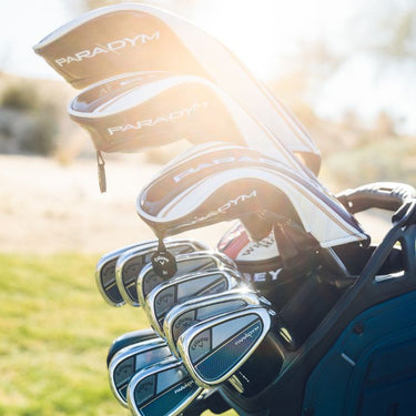 The Callaway Paradym Family all in a golf bag with the back of the club head looking at the camera. With the sun in the background causing some sun glare in the shot. 