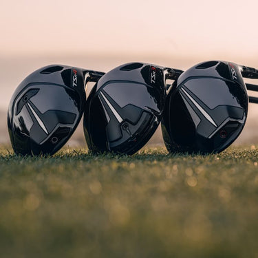 The Titleist TSR Driver line up with the TSR2, 3 and 4 all lying on grass next to each other showing the sole of the driver. 